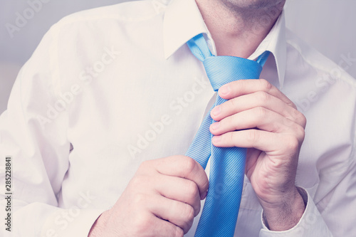 Office Manager tying a tie, man is going to work, man's hands, cropped image, close up