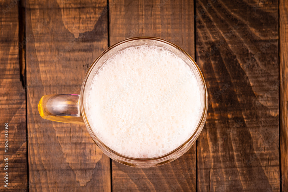 Top view of a jug of very cold beer on a wooden table on a black background. Concept for the oktoberfest party. Top view of a jug of very cold beer on a wooden table on a black background. Concept for the oktoberfest party.