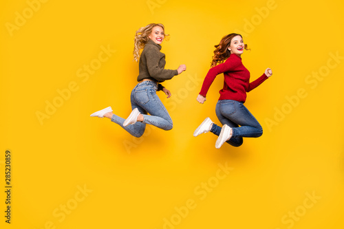 Full size photo of funny ladies jumping high wear knitted sweaters isolated yellow background