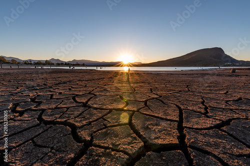 The sun sets setting over a lake it shows the dry cracks in lake bed. On a clear and sunny day in Lake Moogerah, Queensland, Australia