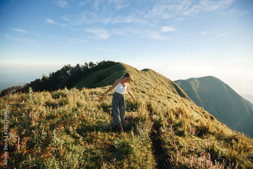 Woman traveler walking in amazing mountains and forest, wanderlust travel concept, space for text, atmospheric moment. Earth day