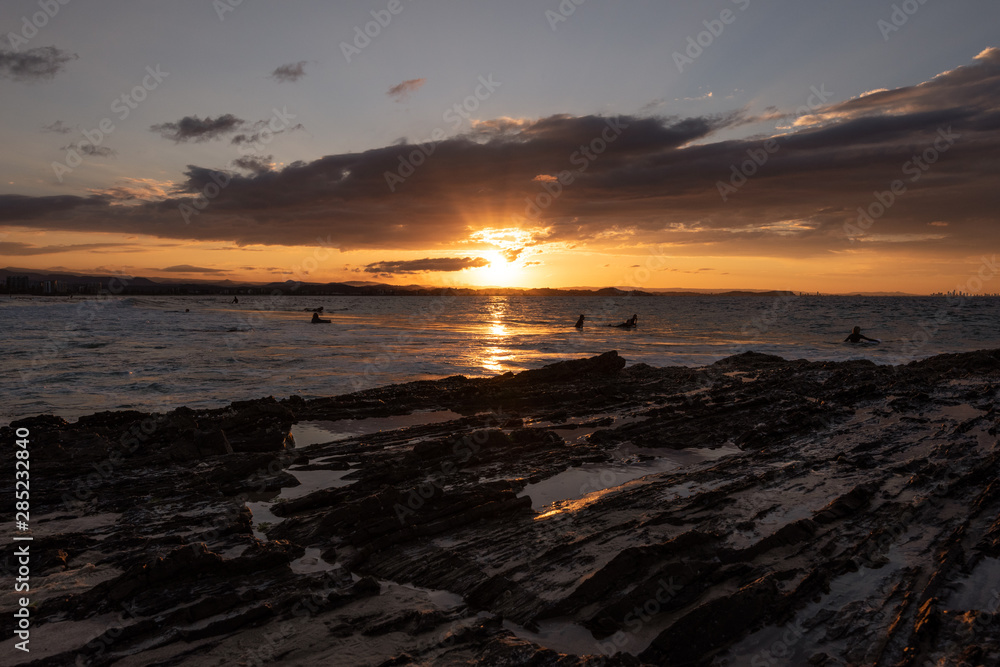 Surfers go out to enjoy the waves during sunset at Snapper Rocks, Queensland, Australia