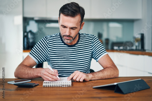 Handsome man sitting at home and managing personal finance