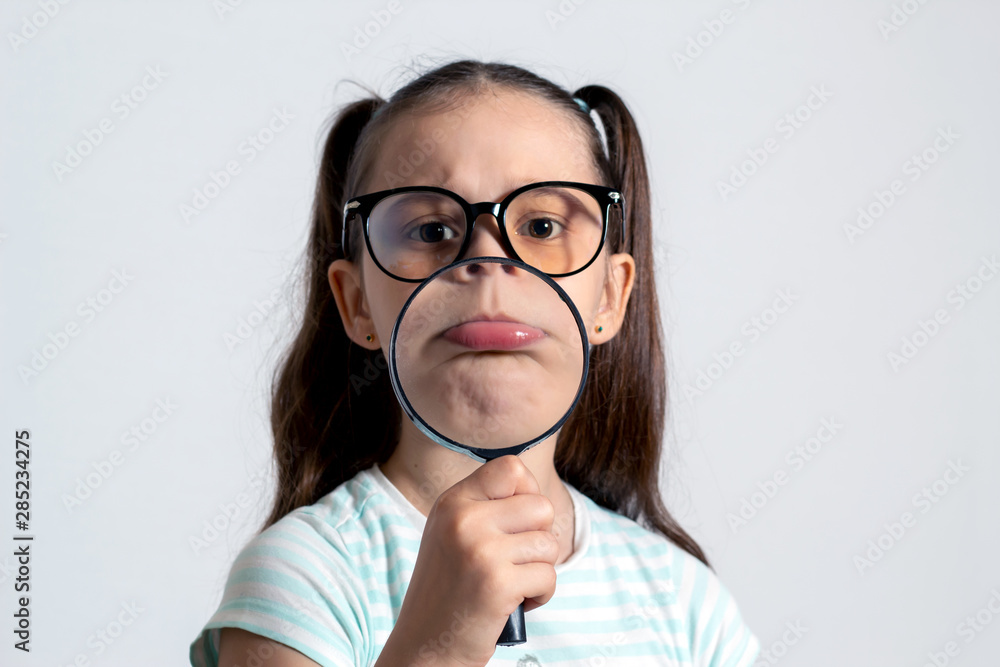 Little girl with a magnifying glass. The child looks like a sad monkey Little girl with a magnifying glass. The child looks like a sad monkey