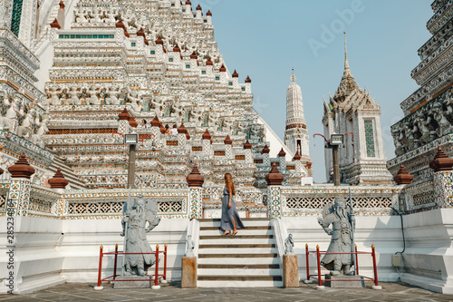 Young caucasian women tourist traveling at Wat Arun Ratchawararam (the Temple of Dawn), one of the famous place in Bangkok, Thailand
