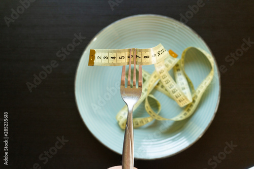 Diet concept - yelow measuring tape on fork