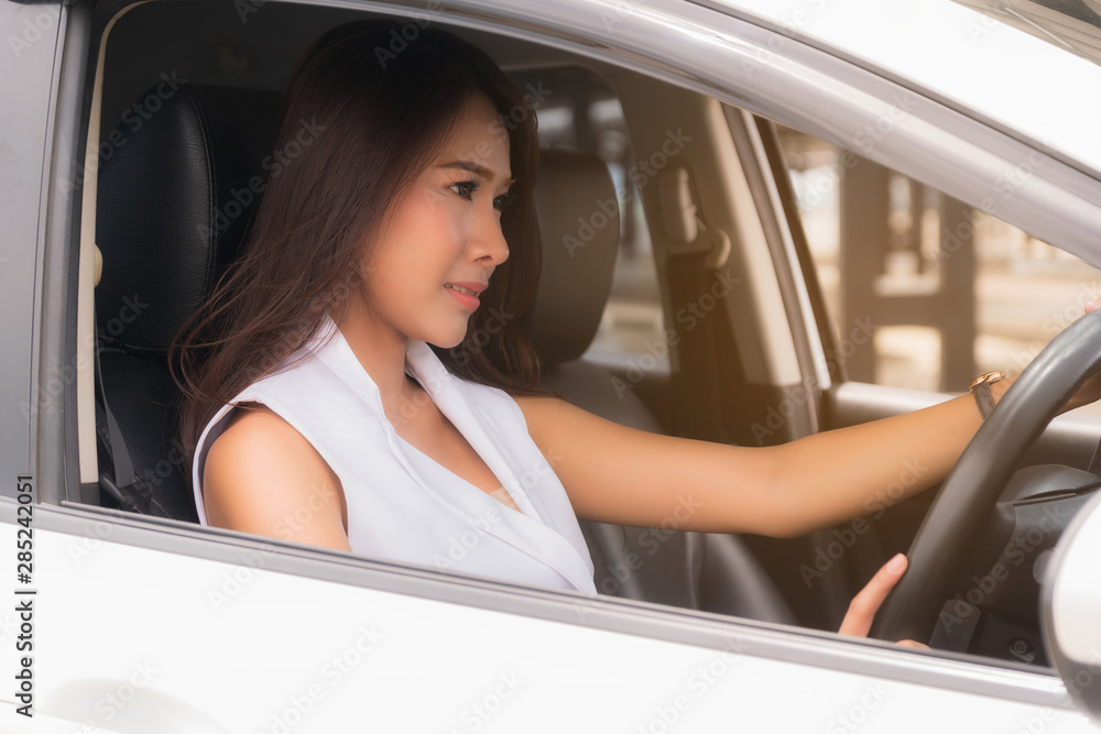 Asian beautiful woman wearing a white shirt Driving a sedan in white, open the car window. in close up view.