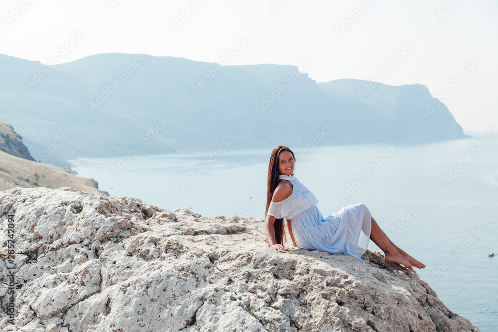 beautiful woman with long hair on a cliff ocean