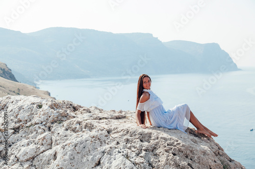 beautiful woman with long hair on a cliff ocean