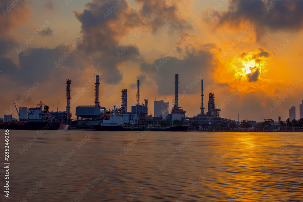 The sun shines through the dark clouds to the oil refinery, Beautiful factory with morning sky-Image
