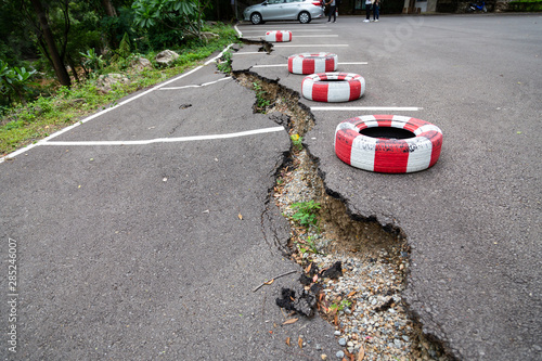 The road in the outdoor public parking lot collapsed,road collapses,cracked asphalt road and fallen,erosion of water,bad construction or earthquake photo