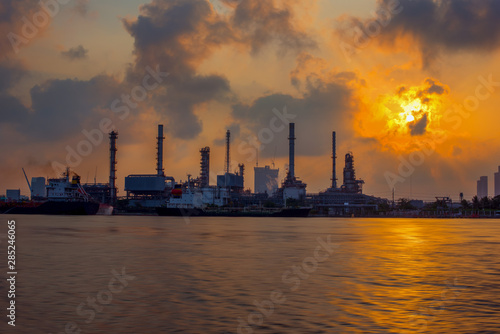 The sun shines through the dark clouds to the oil refinery, Beautiful factory with morning sky-Image