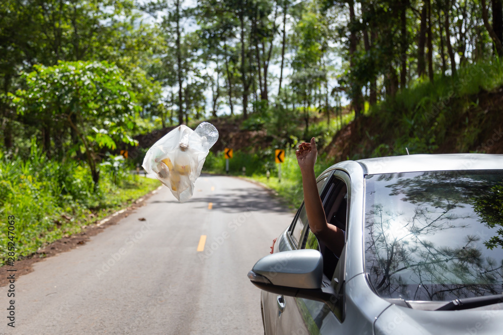 Male driver throwing trash from car window on the road,man’s hand or