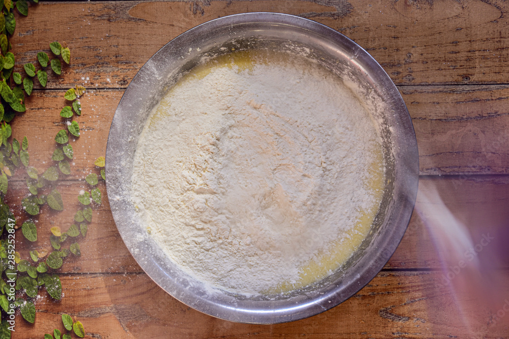 Bowl with ingredients on a wooden surface making a banana bread with flour in the air Bowl with ingredients on a wooden surface making a banana bread with flour in the air