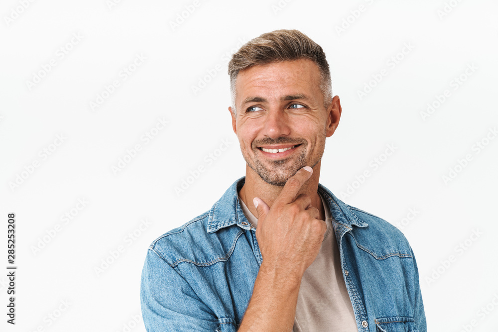 Photo of unshaved guy in denim shirt smiling and looking aside at copyspace Photo of unshaved guy in denim shirt smiling and looking aside at copyspace