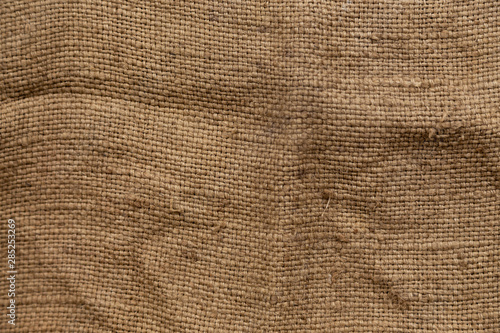 Dark brown background from a textile material with wicker pattern, closeup. Structure of the bronze fabric with texture.