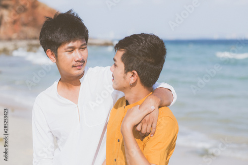 Homosexual portrait young asian couple standing hug together on beach in summer, asia gay going tourism for leisure and relax with romantic and happiness in vacation at sea, LGBT concept. © N_studio