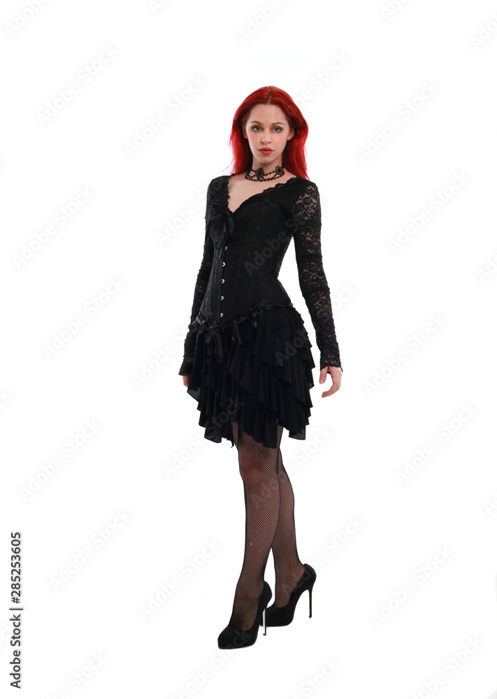 full length portrait of a red haired girl wearing a black gothic gown, Standing pose on a grey studio background. full length portrait of a red haired girl wearing a black gothic gown, Standing pose on a grey studio background.