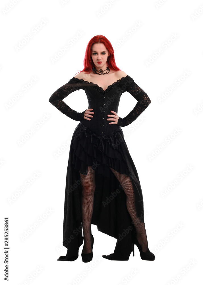 full length portrait of a red haired girl wearing a black gothic gown, Standing pose on a grey studio background. full length portrait of a red haired girl wearing a black gothic gown, Standing pose on a grey studio background.