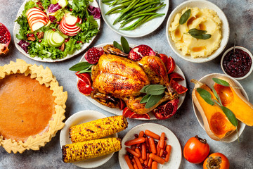 Thanksgiving dinner table with roasted whole chicken or turkey, green beans, mashed potatoes, cranberry sauce and grilled autumn vegetables. Top view, overhead.