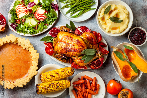 Thanksgiving dinner table with roasted whole chicken or turkey, green beans, mashed potatoes, cranberry sauce and grilled autumn vegetables. Top view, overhead.