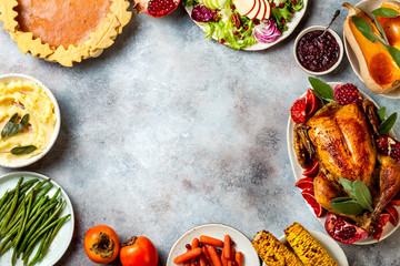 Thanksgiving dinner table with roasted whole chicken or turkey, green beans, mashed potatoes, cranberry sauce and grilled autumn vegetables. Top view, frame.