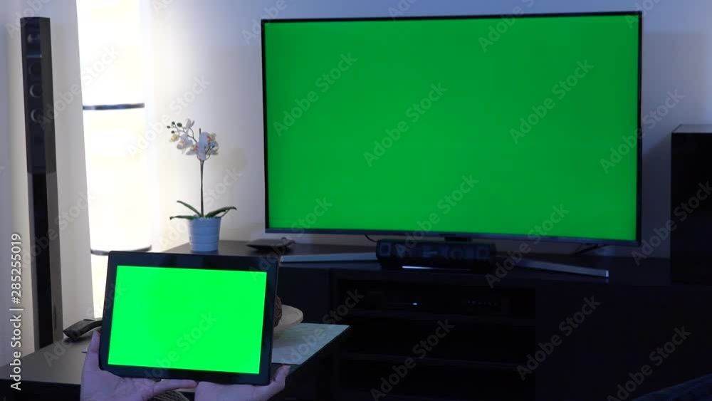 A woman holds out a tablet with green screen in front of camera in a
