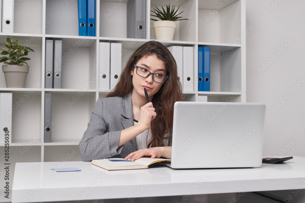 Thoughtful young woman working in office Thoughtful young woman working in office