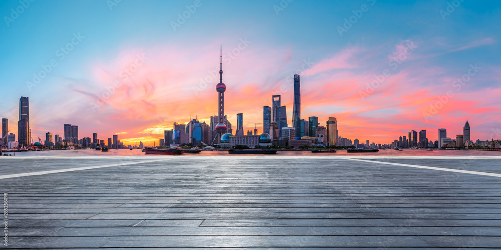 Shanghai skyline and modern buildings with empty wooden board square at sunrise,China.