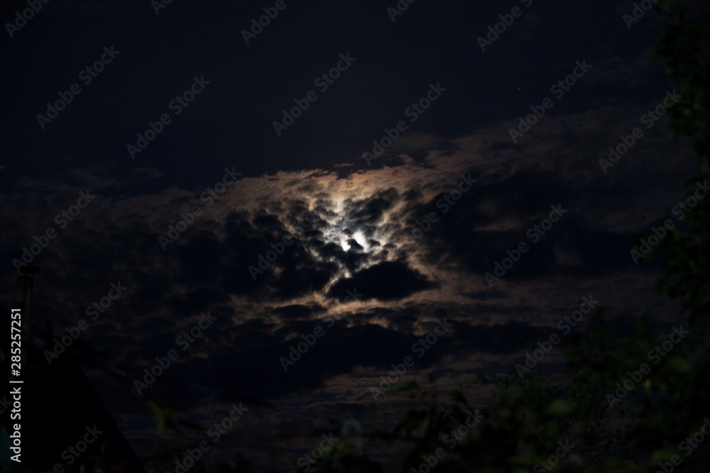 Fototapeta premium moon in the black sky peeps out of the clouds