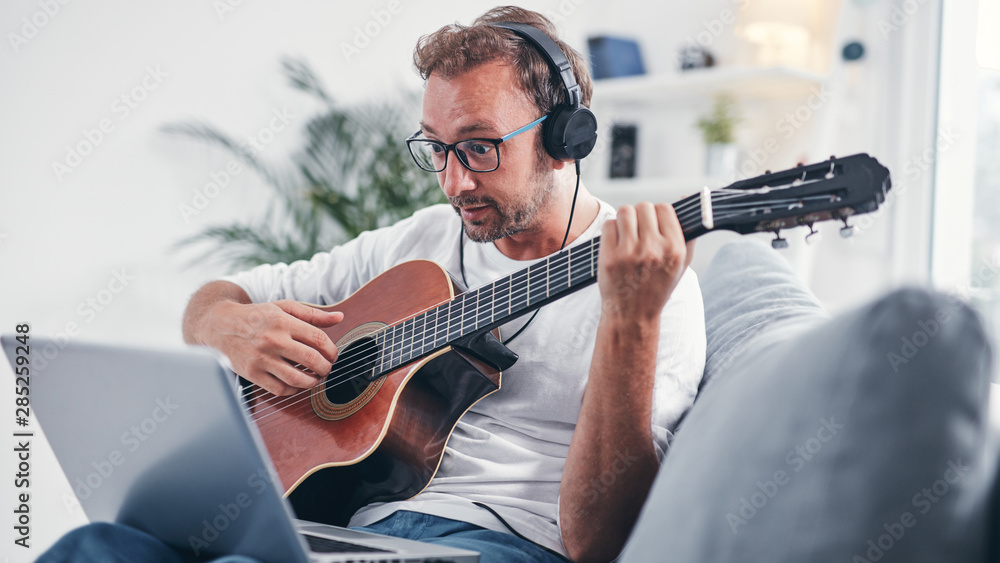 Man playing acoustic guitar in the living room.