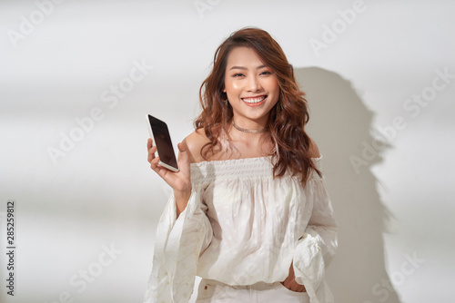 pretty asian woman in casual wear holding smartphone in one hand, dancing