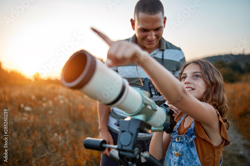 Father and daughter observing the sky with a telescope.