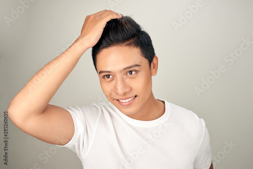 Close up portrait of handsome confident Asian man touching his hair