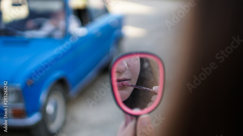 фотографія Young woman draw lips with red pencil looking in the mirror.