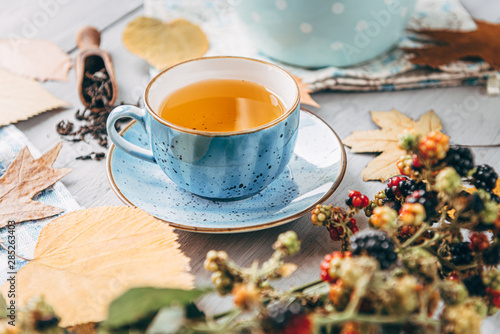 autumn warming tea on a wooden table with autumn tree leaves lying nearby