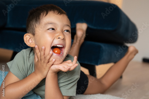Cute boy smiling, eating tomatos