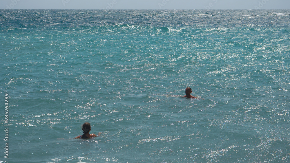 Two people are swimming in the calm Sea Ocean And Blue Sky Background