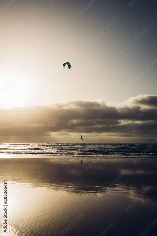 Personas practicando kitesurf al atardecer en la playa de Famara en la isla de Lanzarote