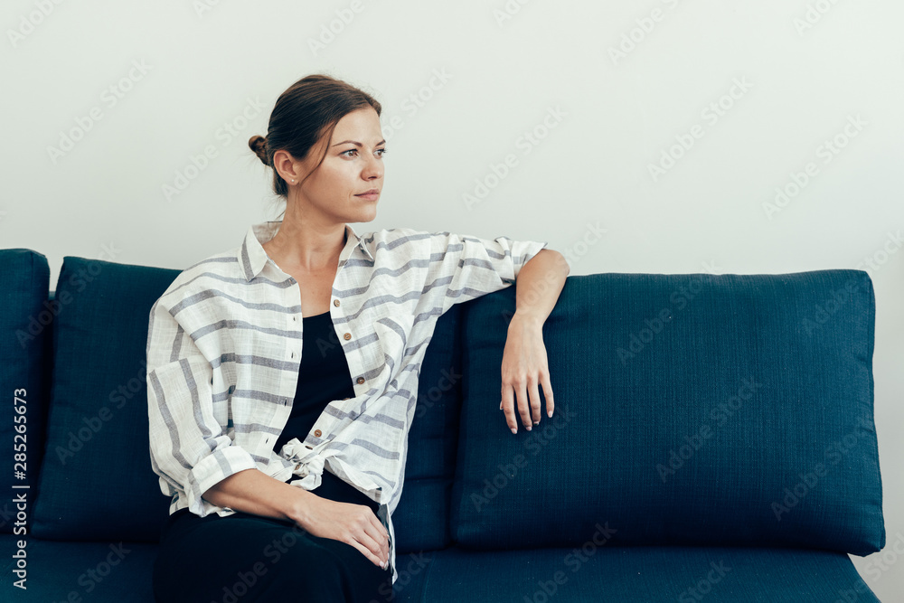 Young adult woman sitting on couch at home Young adult woman sitting on couch at home