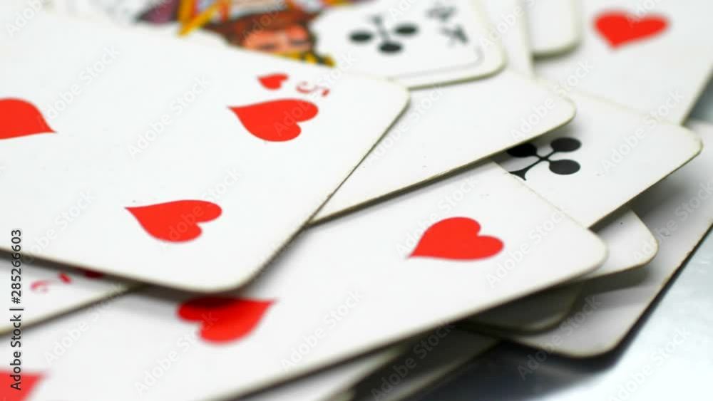 Static, closeup shot, of a pack of cards on a moving table, hearts 5 and the king, in focus, in the middle of the frame