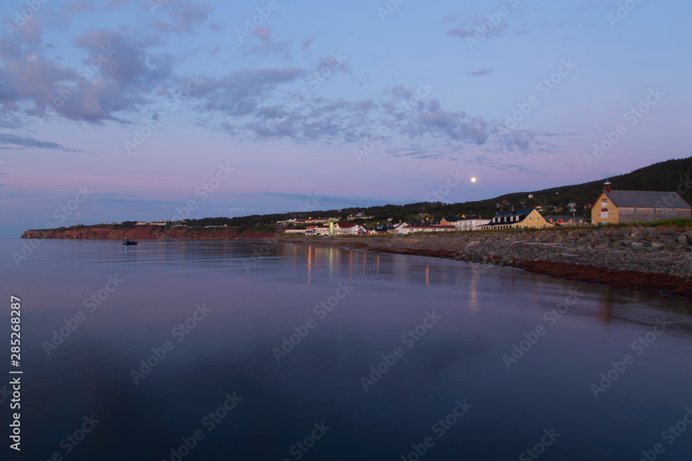 Full moon over the famous Percé village bay seen during a beautiful summer dawn, Quebec, Canada