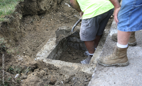 A concrete construction worker digs around a drain after the concrete was dug up.