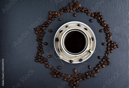 a Cup of coffee on a stone Board with scattered coffee beans, an abstraction top view, flat lay
