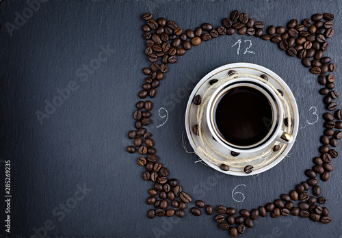 a Cup of coffee on a stone Board with scattered coffee beans, an abstraction top view, flat lay