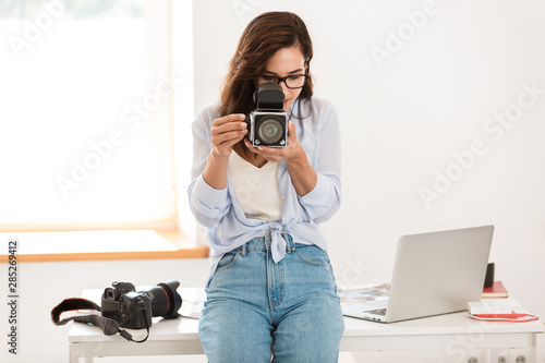 Amazing young pretty photographer woman in office holding retro old camera. © Drobot Dean