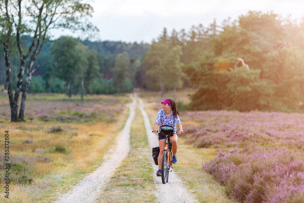 Young woman riding bicycle in the countryside, Hoge Veluwe, Holland