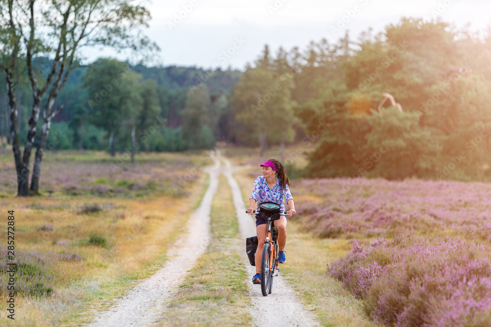 Young woman riding bicycle in the countryside, Hoge Veluwe, Holland Young woman riding bicycle in the countryside, Hoge Veluwe, Holland