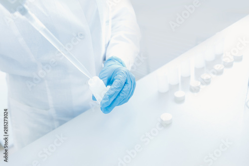 Scientist in white coat takes analysis from paragraph with pipette. Chemistry biological background concept
