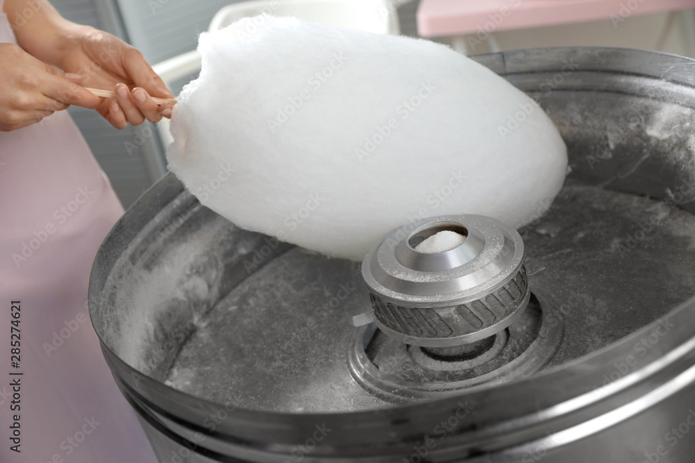 Woman making cotton candy using modern machine indoors, closeup